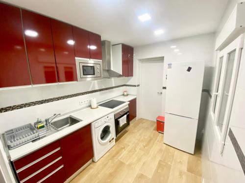 a kitchen with red cabinets and a white refrigerator at Apartamento Colón in Getafe