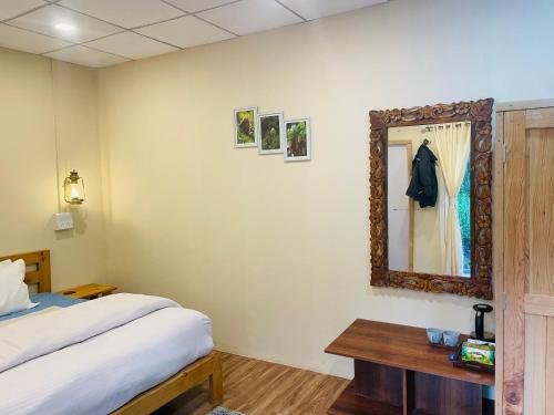a bedroom with a bed and a mirror on the wall at Mystic Vibes - Jibhi in Jibhi