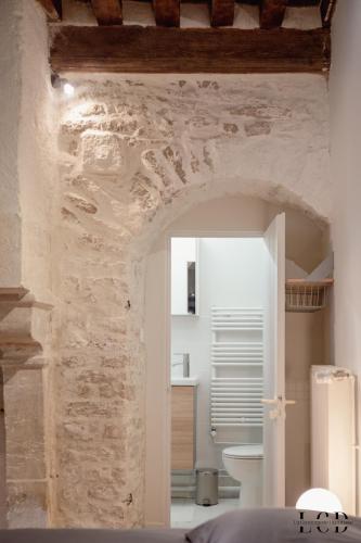 une chambre avec un mur en pierre et une salle de bain dans l'établissement Le Buffon, à Dijon