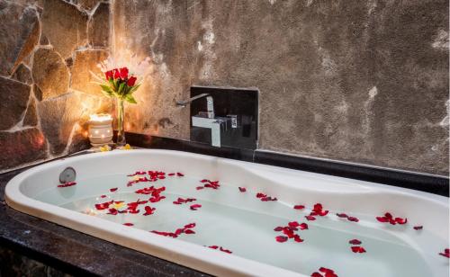 eine Badewanne gefüllt mit roten Blumen in einem Badezimmer in der Unterkunft Pendopo Perwitasari in Timuran
