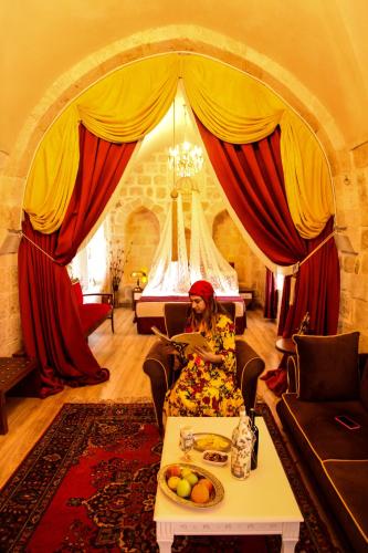 a woman sitting in a living room with a table at Tuğhan Hotel in Mardin