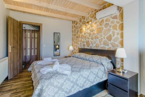 a bedroom with a bed and a stone wall at INFINITY BLUE in Agní
