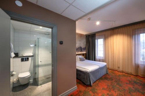 a bedroom with a bed and a shower and a toilet at Clarion Collection Hotel Bergmästaren in Falun