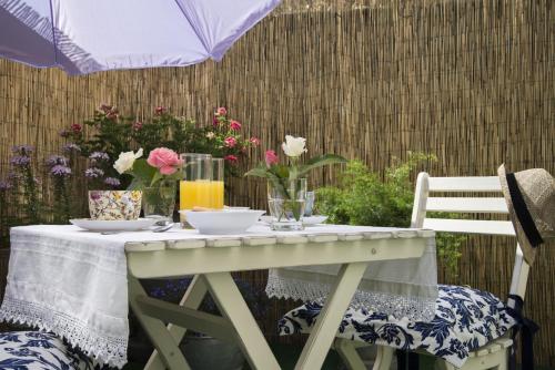 Il Giardino di Ortensia B&B في بيينْتينا: طاولة بيضاء عليها زهور مع كرسيين