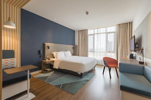 a bedroom with a bed and a blue wall at Holiday Inn Express Zhangjiagang Free Trade Zone, an IHG Hotel in Zhangjiagang