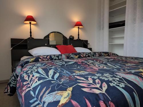 a bedroom with a bed with a colorful blanket and two lamps at Maison Au P'tit Bonheur in Argenton-sur-Creuse