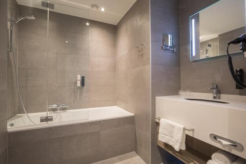 a bathroom with a tub and a sink at Ramada The Hague Scheveningen in Scheveningen