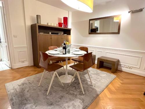 - une salle à manger avec une table, des chaises et un miroir dans l'établissement L'appartement Pierre Charron, à Paris