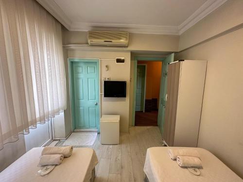um pequeno quarto com 2 camas e uma televisão em Hikmethan Otel em Kusadası