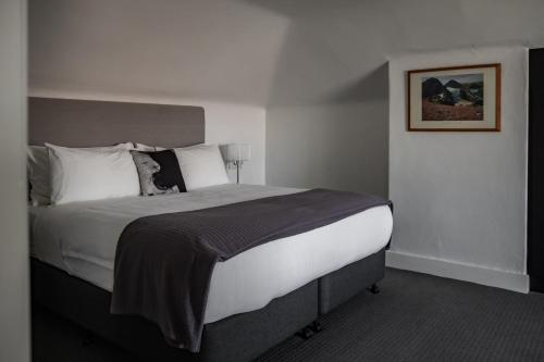 a bedroom with a large bed with white sheets and pillows at Sanctum Boutique Apartments in Hobart