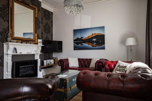 a living room with a leather couch and a fireplace at Sanctum Boutique Apartments in Hobart