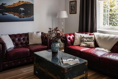 una sala de estar con dos sofás y una mesa con flores. en Sanctum Boutique Apartments, en Hobart