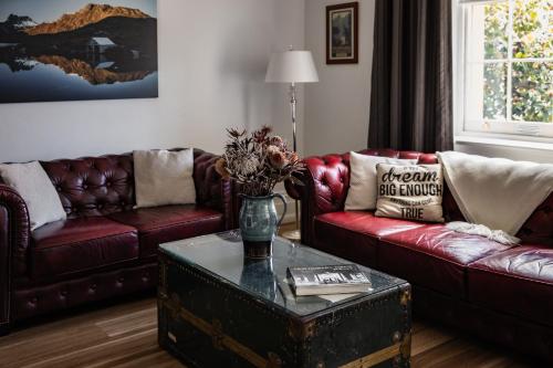 a living room with two couches and a table with flowers on it at Sanctum Boutique Apartments in Hobart