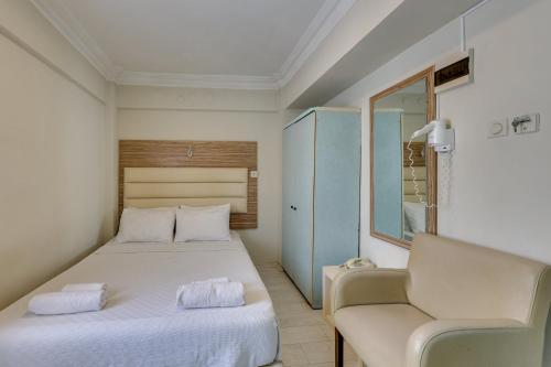 um quarto com uma cama branca e uma cadeira em Hikmethan Otel em Kusadası