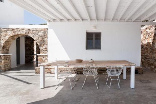 a wooden table and chairs under a white wall at Windmill House with private pool and breathtaking views in Andiparos