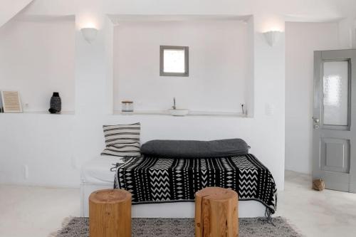 a white room with a bed and two wooden stools at Windmill House with private pool and breathtaking views in Andiparos