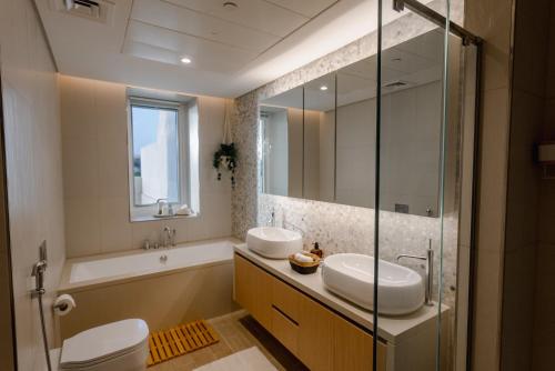 a bathroom with two sinks and a tub and a toilet at Voyage Private Pool & Beach At Your Doorstep in Abu Dhabi