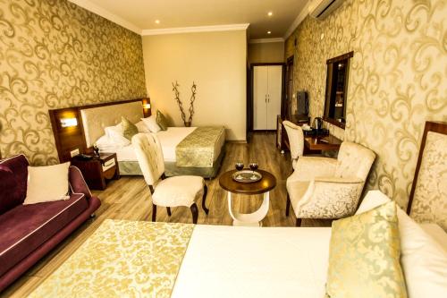 a hotel room with two beds and a couch at Tuğhan Hotel in Mardin