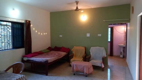 a living room with a bed and chairs in it at Terrace House Goa in Arambol
