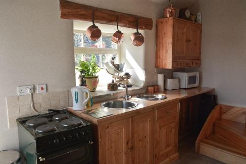 a kitchen with a sink and a stove and a window at West end cottage and shippon in Eyam