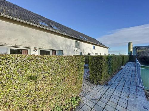 a hedge in front of a house and a building at Blauwhof - Steenkerke in Veurne