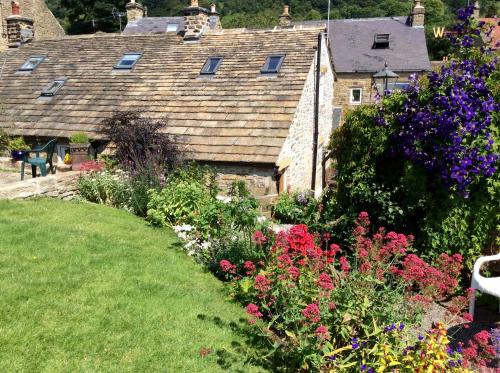 a garden of flowers in front of a house at West end cottage and shippon in Eyam