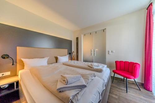 a bedroom with a large bed and a red chair at Resort Deichgraf Resort Deichgraf 31-07 in Wremen