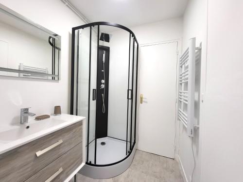 La salle de bains est pourvue d'une douche en verre et d'un lavabo. dans l'établissement Les Entrepreneurs - Appartements neufs et spacieux, proche RER C et Aéroport Orly, à Morangis