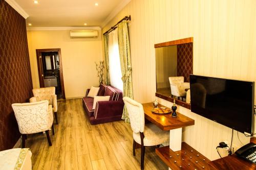 a living room with a television and a table with chairs at Tuğhan Hotel in Mardin