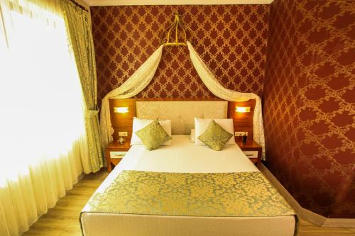 a bedroom with a large bed with a red wall at Tuğhan Hotel in Mardin