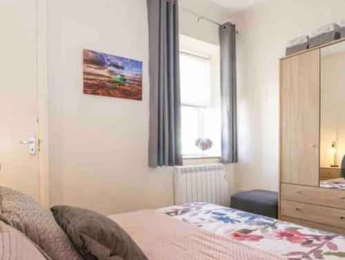 a bedroom with a bed and a dresser and a window at The Butcher's Flat Seahouses in Seahouses