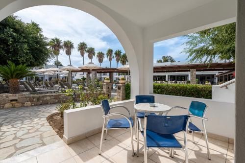 a patio with a table and chairs and palm trees at Palladium hotel in Marmari
