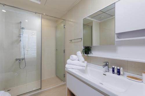a bathroom with a shower and a sink and a mirror at Maison Privee - Modern Urban Retreat in the Heart of Dubai Marina in Dubai