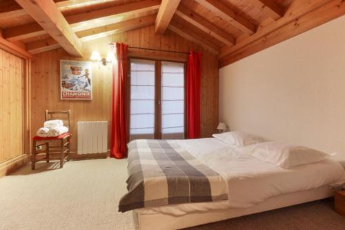 a bedroom with a bed with red curtains and a window at Chalet Ancelles - Les Praz - Golf - Vue Mont-Blanc - Randonnées in Chamonix-Mont-Blanc