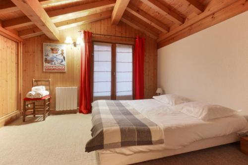 une chambre avec un lit avec des rideaux rouges et une fenêtre dans l'établissement Chalet Ancelles - Les Praz - Golf - Vue Mont-Blanc - Randonnées, à Chamonix-Mont-Blanc