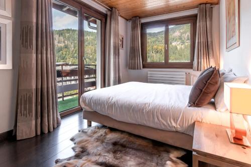 une chambre avec un lit et une grande fenêtre dans l'établissement Les Marmottes - Renovated and cozy apart - View of the mountains, aux Houches