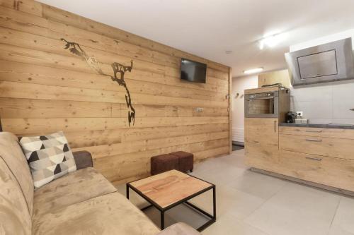 - un salon avec un mur en bois, un canapé et une table dans l'établissement Perce-Neige - Centre Chamonix, à Chamonix-Mont-Blanc