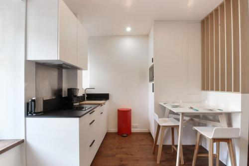 une cuisine avec des armoires blanches et une table et des chaises dans l'établissement Vallot - Chamonix Centre, à Chamonix-Mont-Blanc