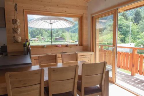 a dining room with a table and chairs and a large window at Le Lac - Servoz - Appartement paisible de 70m² in Les Houches