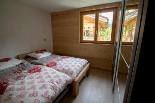 two beds in a small room with a window at Le Lac - Servoz - Appartement paisible de 70m² in Les Houches