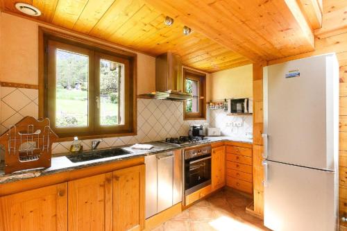 Il comprend une cuisine avec un réfrigérateur blanc et des plafonds en bois. dans l'établissement L'Ecrin des Pècles - Centrale - Rénové - Immense Terrasse Face au Mont-Blanc, à Chamonix-Mont-Blanc