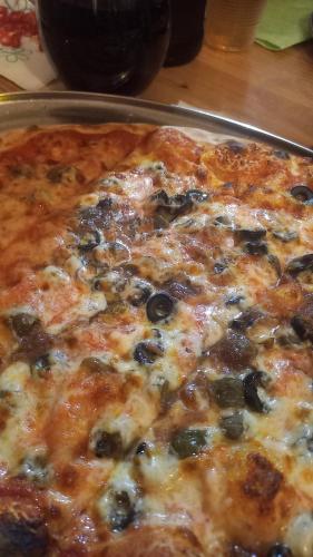 a pizza with olives and cheese on a pan at PALAZZO NOVECENTO Centro Storico in Lecco
