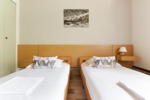 duas camas num quarto com lençóis brancos em Le Crêtet Mont-Blanc em Chamonix-Mont-Blanc