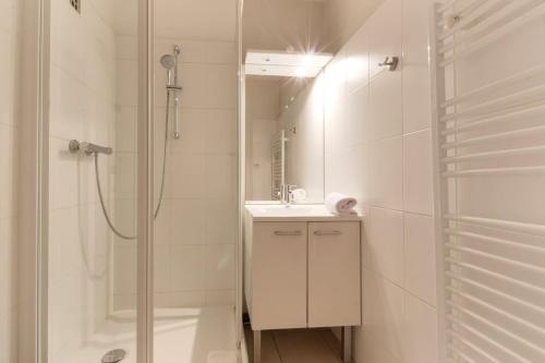 La salle de bains blanche est pourvue d'une douche et d'un lavabo. dans l'établissement Les Pècles Mt Blanc - Chamonix Center, à Chamonix-Mont-Blanc