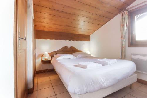 - une chambre avec un lit blanc et un plafond en bois dans l'établissement Le Goûter - Ski-in ski-out - Indoor Pool, aux Houches