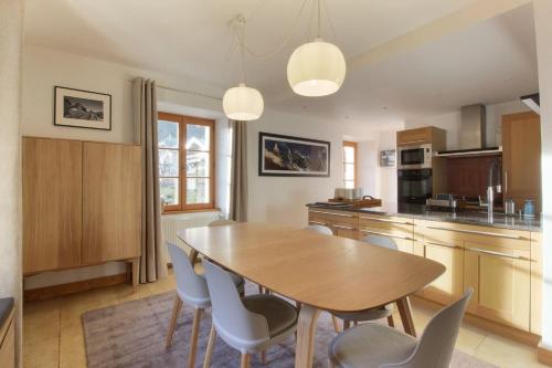 une cuisine avec une table et des chaises en bois dans l'établissement Les Alpins - Centre de Chamonix - Rénové avec Jardin et vue imprenable sur le MontBlanc, à Chamonix-Mont-Blanc