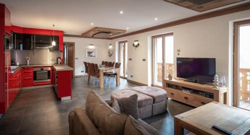 uma sala de estar com um sofá e uma cozinha com armários vermelhos em Les Ecureuils -Rénové 100m2 - 8per - Skis aux Pieds - Vue sur la Montagne em Les Houches