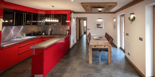 une cuisine avec des placards rouges et une table en bois dans l'établissement Les Ecureuils -Rénové 100m2 - 8per - Skis aux Pieds - Vue sur la Montagne, aux Houches