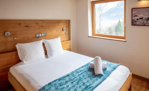 une chambre avec un lit avec un ours en peluche dessus dans l'établissement Les Ecureuils -Rénové 100m2 - 8per - Skis aux Pieds - Vue sur la Montagne, aux Houches