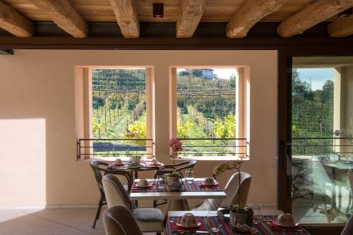 ein Esszimmer mit einem Tisch und 2 Fenstern in der Unterkunft Casa Valdo Country House in Valdobbiadene